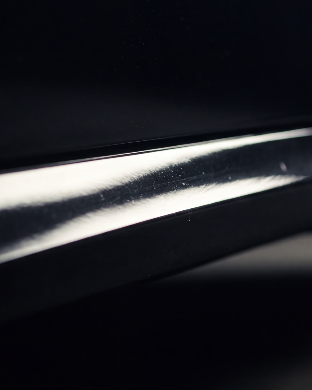 Macro de pintura negra con brillo de espejo bajo luz dirigida