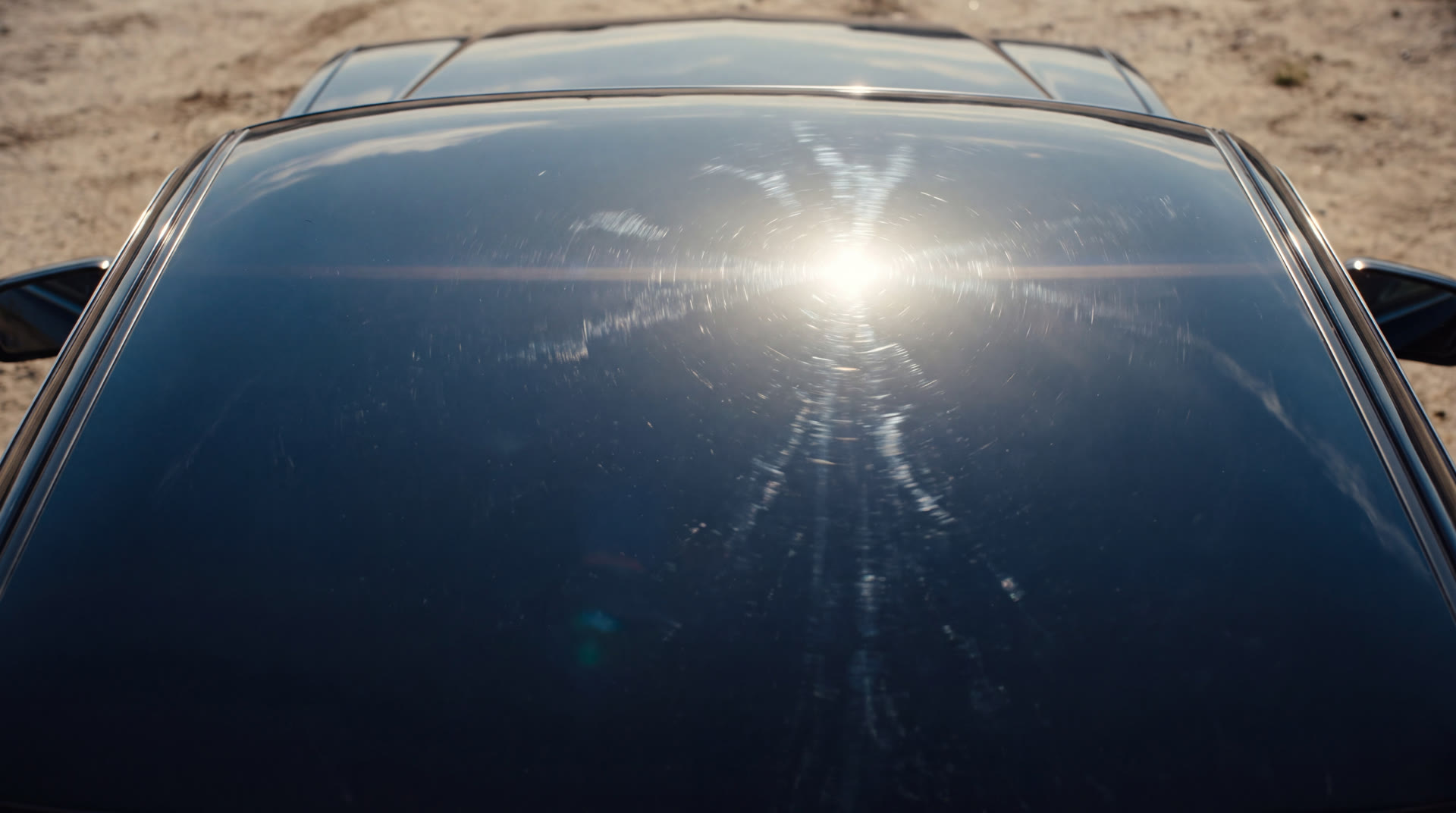 Sol de mediodía reflejándose con fuerza sobre el techo de un auto oscuro, con distorsión de calor visible en el aire